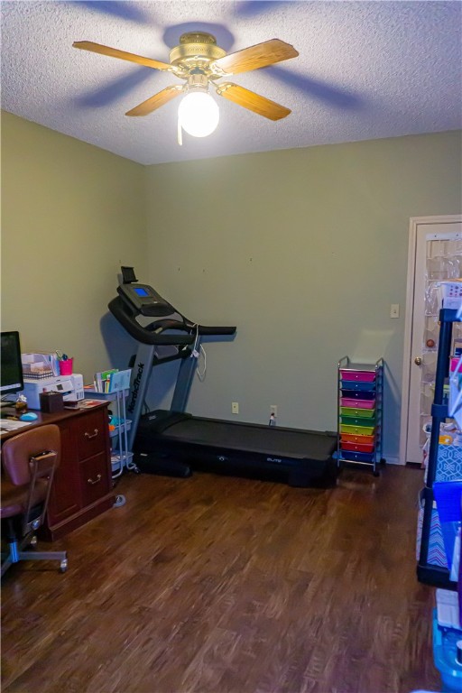 office area with ceiling fan, dark wood-type flooring, and a textured ceiling