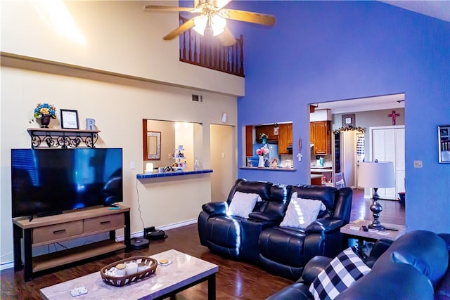 living area with wood finished floors, a ceiling fan, visible vents, baseboards, and a high ceiling