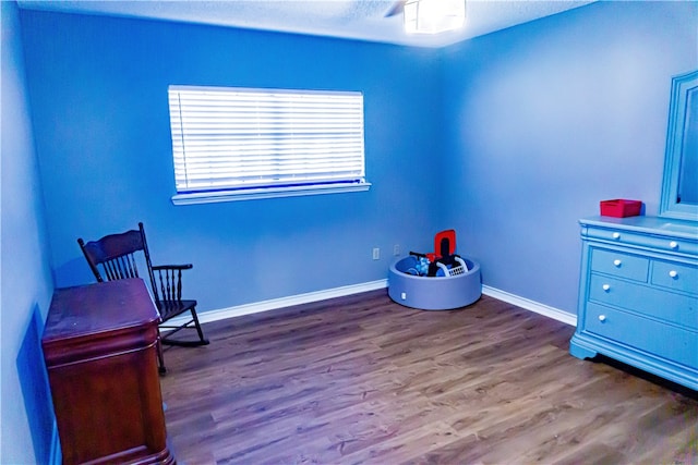 living area with baseboards and wood finished floors