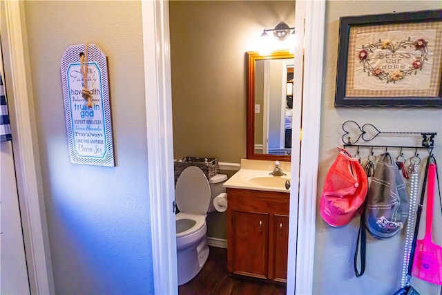 bathroom with toilet, wood finished floors, and vanity