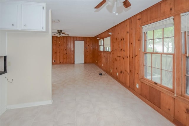 613 Brawner Pkwy, Corpus Christi, TX 78411 - empty room featuring a ceiling fan, wood walls, healthy amount of natural light, baseboards, and light flooring