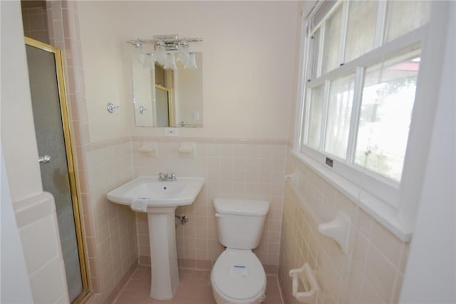 613 Brawner Pkwy, Corpus Christi, TX 78411 - bathroom with a shower stall, toilet, tile walls, a wainscoted wall, and a sink