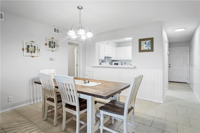 5973 State Highway 361 Unit 332, Port Aransas, TX 78373 - dining area featuring a chandelier, light tile patterned flooring, and wainscoting