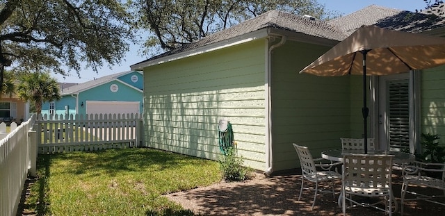 view of side of property with a garage, a lawn, and a patio area