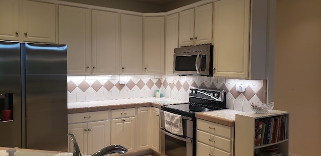 kitchen with tile countertops, white cabinetry, decorative backsplash, and stainless steel appliances