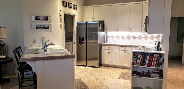 kitchen with tile counters, appliances with stainless steel finishes, and white cabinetry