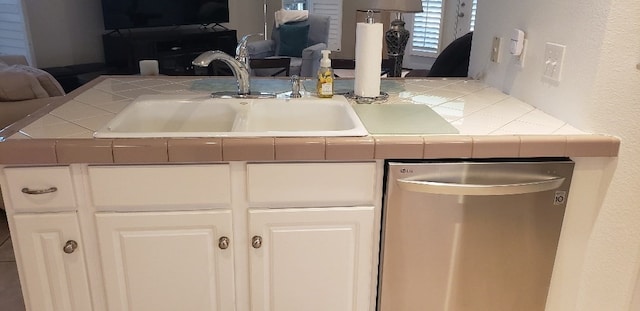 kitchen with white cabinetry, stainless steel dishwasher, sink, and tile counters