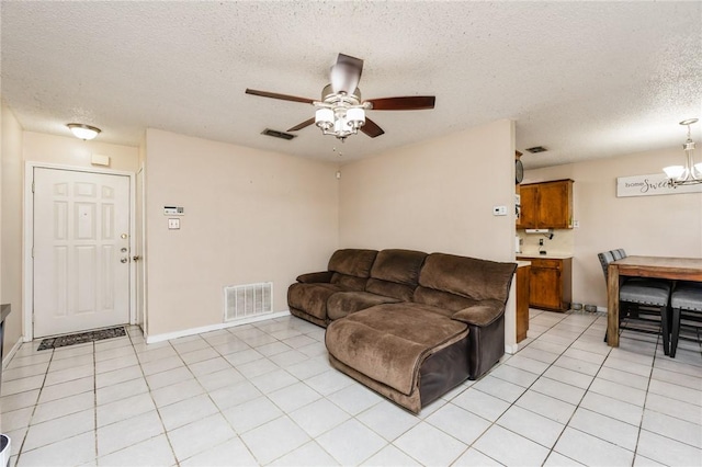 tiled living room with ceiling fan with notable chandelier and a textured ceiling