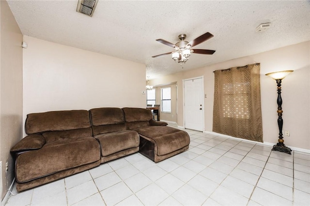 living room with light tile patterned floors, ceiling fan, and a textured ceiling