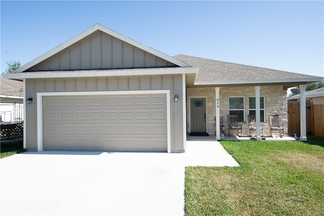 view of front of property featuring a porch, a front lawn, and a garage