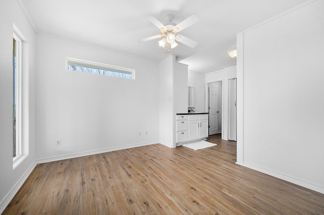 spare room with ceiling fan, light wood-type flooring, and ornamental molding