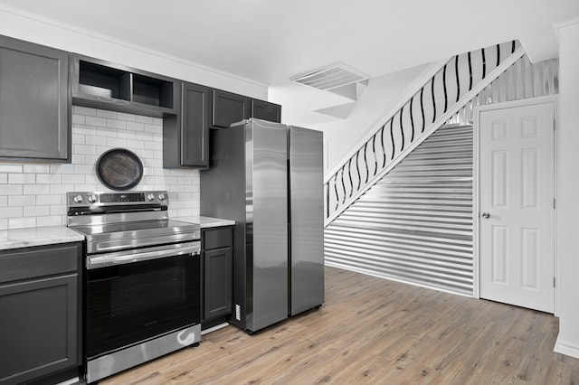 kitchen featuring light stone countertops, light wood-type flooring, appliances with stainless steel finishes, and tasteful backsplash