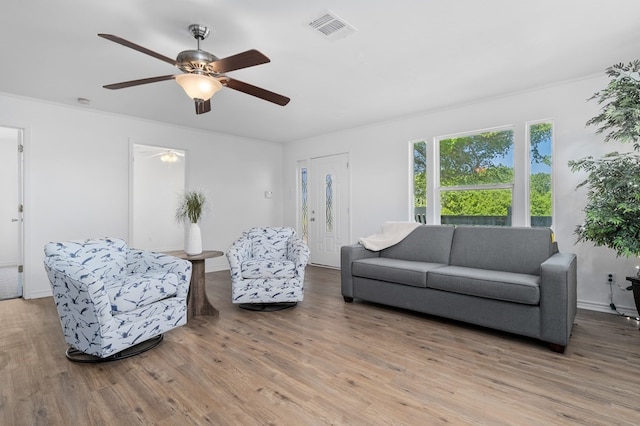 living room featuring light hardwood / wood-style floors, ceiling fan, and crown molding