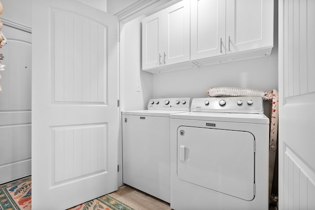 laundry area featuring cabinets, independent washer and dryer, and light hardwood / wood-style flooring