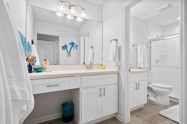 bathroom featuring wood-type flooring, toilet, vanity, and a shower with shower door