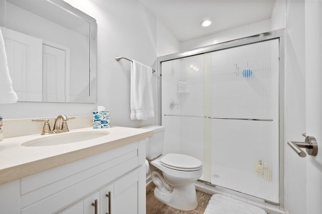 bathroom with vanity, a shower with door, and toilet