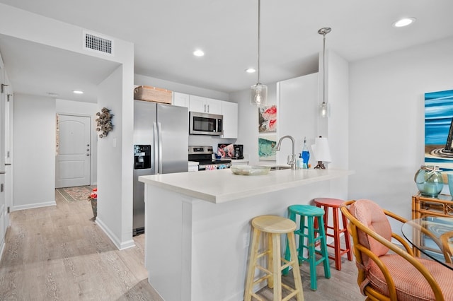 kitchen with sink, a breakfast bar, appliances with stainless steel finishes, white cabinets, and kitchen peninsula