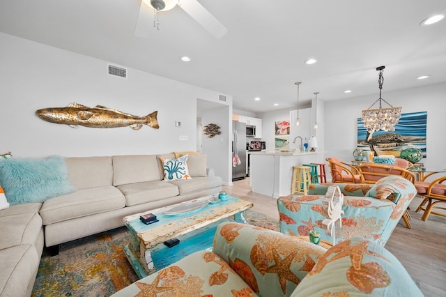 living room featuring sink, ceiling fan with notable chandelier, and light hardwood / wood-style floors