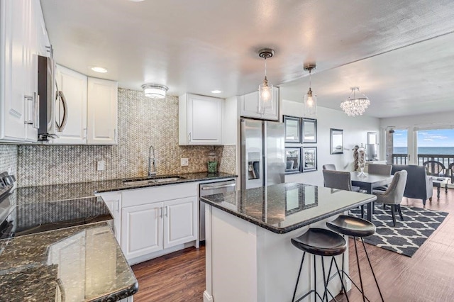 14810 Windward Dr Unit 209, Corpus Christi, TX 78418 - kitchen featuring a sink, appliances with stainless steel finishes, dark wood-type flooring, white cabinetry, and a kitchen bar