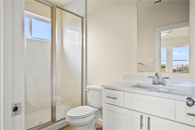 bathroom featuring toilet, vanity, an enclosed shower, and ceiling fan