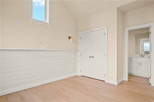 interior space with sink, vaulted ceiling, and light hardwood / wood-style floors