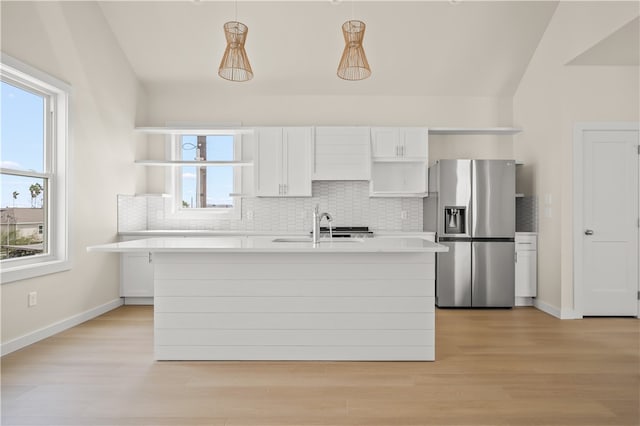 kitchen with light hardwood / wood-style floors, vaulted ceiling, stainless steel refrigerator with ice dispenser, hanging light fixtures, and white cabinetry