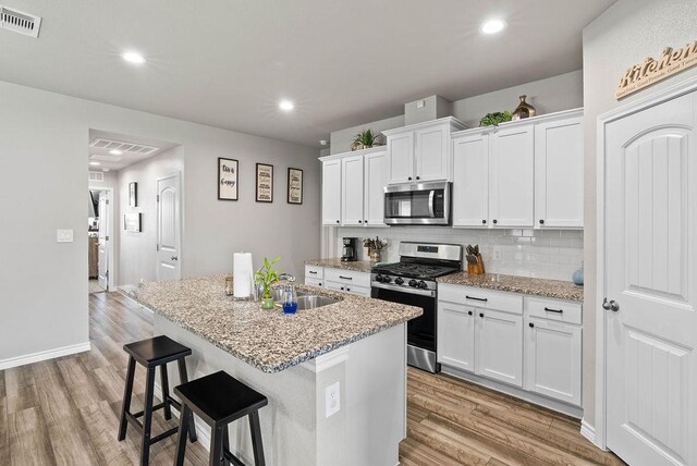 7753 Lariat Toss Dr, Corpus Christi, TX 78414 - kitchen featuring appliances with stainless steel finishes, light wood-style floors, backsplash, a kitchen breakfast bar, and recessed lighting