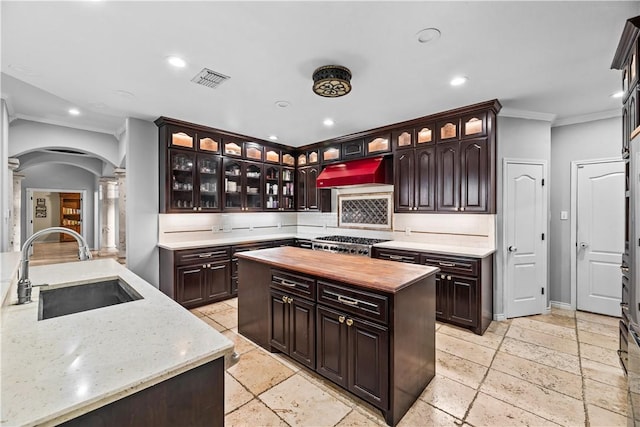 5514 King Trl, Corpus Christi, TX 78414 - kitchen with a sink, exhaust hood, crown molding, butcher block counters, and decorative columns