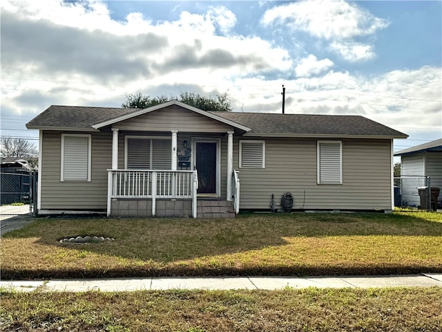 view of front of property with a shingled roof, covered porch, fence, and a front lawn