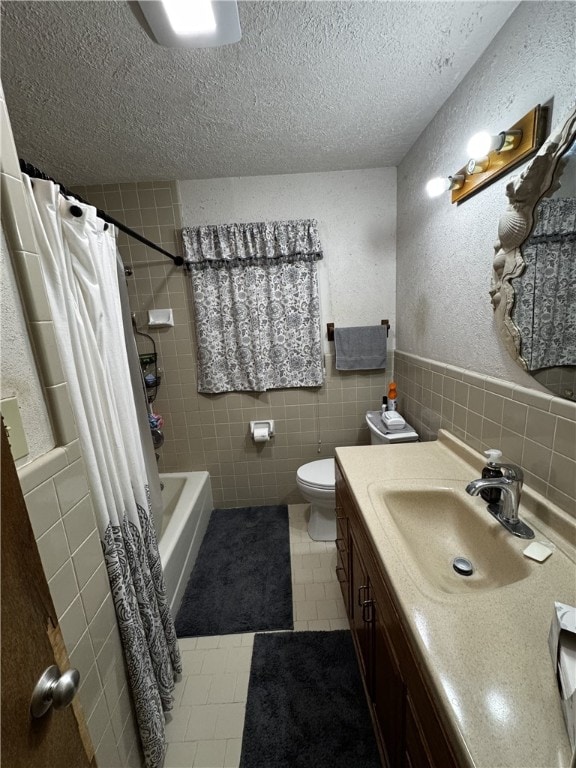 full bath featuring a textured ceiling, vanity, tile walls, and tile patterned floors