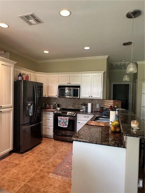 113 N Santa Clara Dr, Rockport, TX 78382 - kitchen featuring appliances with stainless steel finishes, a peninsula, ornamental molding, white cabinets, and dark stone countertops