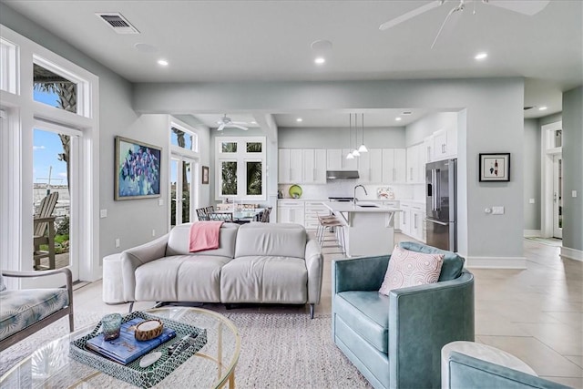 kitchen featuring an island with sink, sink, white cabinets, light stone counters, and stainless steel appliances