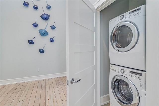 washroom featuring hardwood / wood-style flooring and stacked washer / dryer