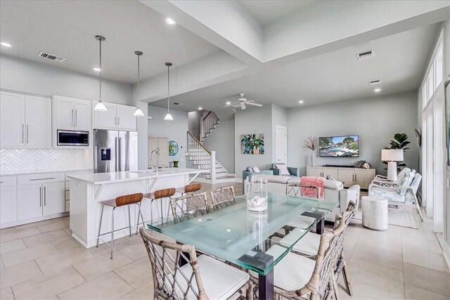 kitchen with light stone countertops, appliances with stainless steel finishes, a kitchen island with sink, and white cabinets