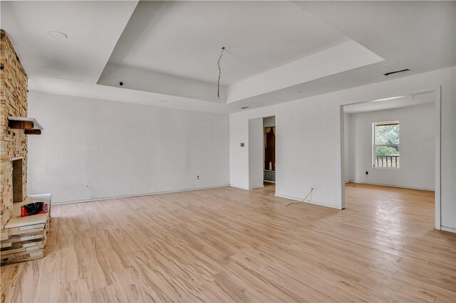 5367 Paloma Trl, Robstown, TX 78380 - unfurnished living room with a raised ceiling, a fireplace, light wood finished floors, and baseboards