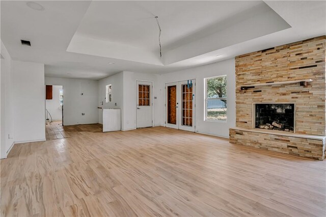 5367 Paloma Trl, Robstown, TX 78380 - unfurnished living room featuring a tray ceiling, light wood-type flooring, healthy amount of natural light, and a stone fireplace