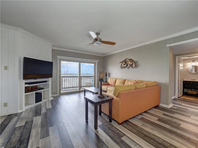 living area with ornamental molding, ceiling fan, baseboards, and wood finished floors