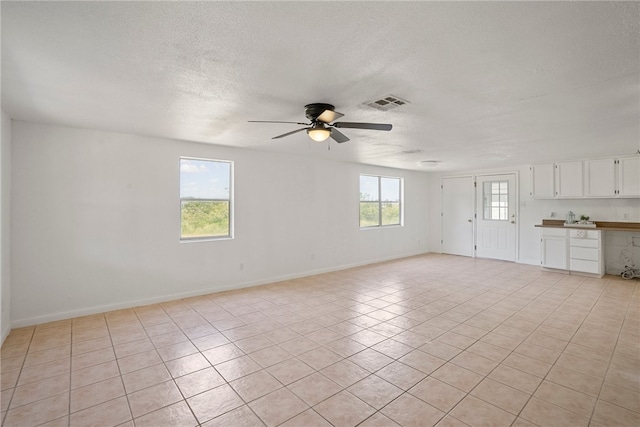 tiled spare room with a textured ceiling, a wealth of natural light, and ceiling fan