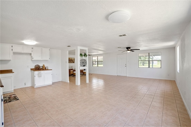 unfurnished living room featuring light tile patterned flooring, ceiling fan, and a textured ceiling