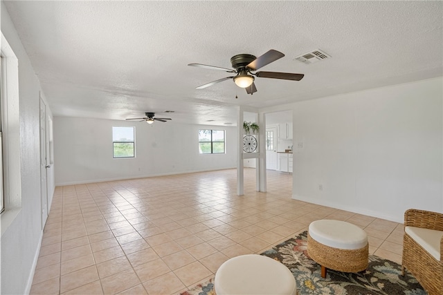 tiled living room with a textured ceiling and ceiling fan