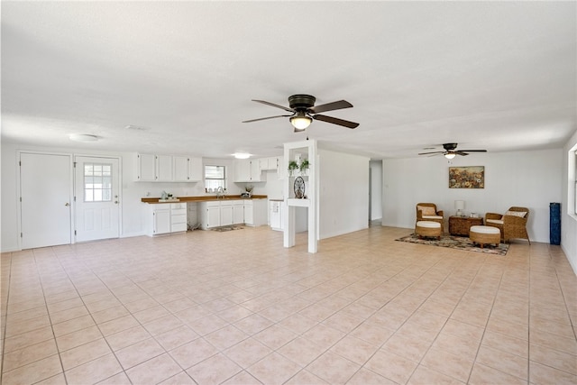 unfurnished living room featuring ceiling fan, sink, and light tile patterned floors