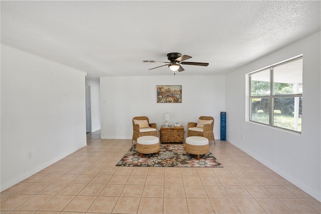 sitting room with a textured ceiling, light tile patterned floors, and ceiling fan