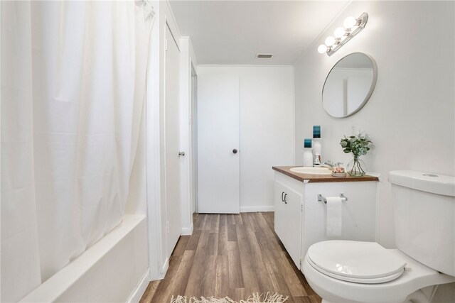 full bathroom featuring shower / bath combo with shower curtain, vanity, hardwood / wood-style flooring, and toilet