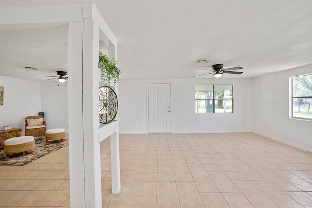 unfurnished living room featuring ceiling fan, plenty of natural light, and light tile patterned floors