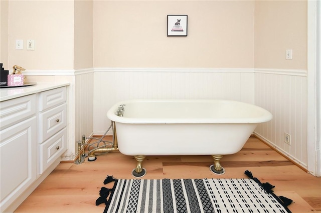 full bath with a wainscoted wall, a freestanding bath, and wood finished floors