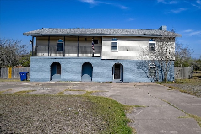 view of front of home featuring driveway, a chimney, and fence