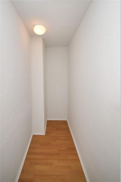 hall featuring light wood-style flooring and baseboards