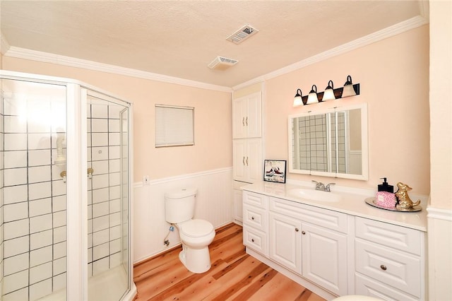 full bathroom featuring wood finished floors, a wainscoted wall, visible vents, a stall shower, and toilet