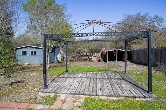 wooden terrace featuring an outdoor structure and fence