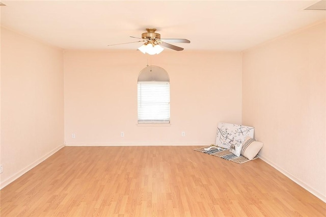 spare room featuring baseboards, ceiling fan, and light wood finished floors